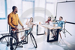 multicultural business people greeting african american colleague with bicycle