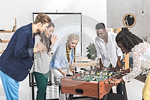 multicultural businessmen and businesswomen playing table football together