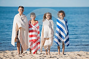 multicultural children in colorful towels standing at seaside and looking