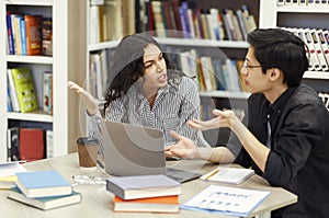 Multicultural couple sharing ideas about coursework in library