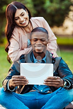 multicultural couple taking selfie with tablet at the