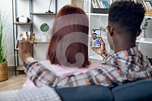 Multicultural couple using mobile for video call with family