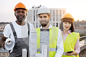 Multicultural designers with equipment posing on rooftop