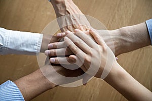 Multicultural employees stacking hands together engaged in team building