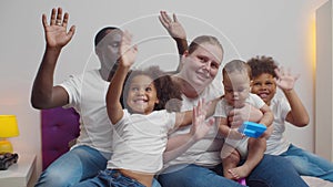 Multicultural family waving and making video call together at home. Realtime