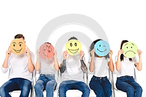 multicultural friends in blue jeans sitting on chairs and holding multicolored signs isolated photo