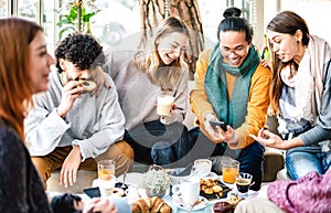 Multicultural friends playing with mobile phone at coffee bar - People having fun together at cafeteria