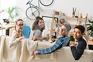 multicultural friends sitting on sofa and looking