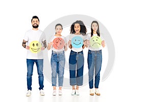 multicultural friends in white T-shirts holding round, multicolored signs with different face expressions and looking at camera is