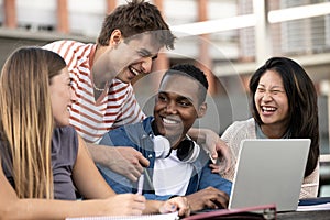 Multicultural group of people working together with a laptop.Young happy friends laughing outside using computer and