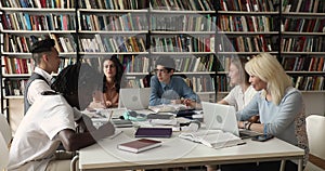 Multicultural group of students studying sit at table in library