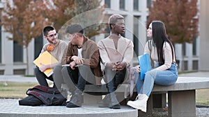 Multicultural group of students talking relaxed sitting outdoors