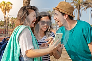 Multicultural group of trendy young friends laughing looking the smartphone.