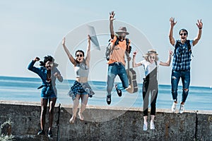 multicultural group of young friends jumping of