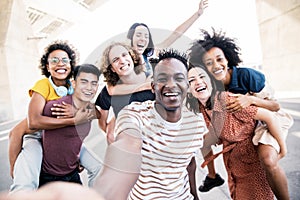 Multicultural happy friends having fun taking group selfie portrait on city street