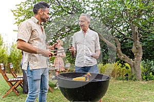 Multicultural mature friends around the barbecue smiling happy and laughing together. Joy concept.