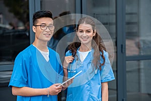 multicultural medical students holding tablet and looking at camera