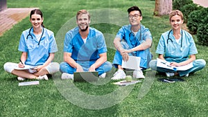 multicultural medical students sitting on grass and looking