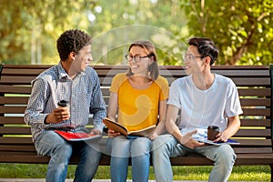 Multicultural Millennials Talking Sitting On Bench Outside After College Classes