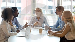 Multicultural professional team colleagues having conversation sit at conference table