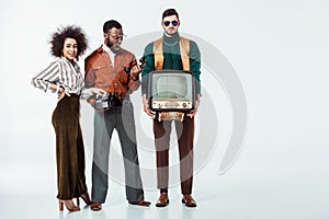 multicultural retro styled friends holding vintage television and telephone
