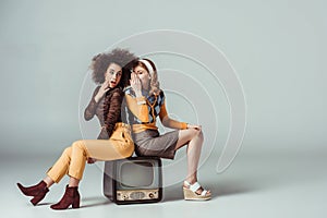 multicultural retro styled girls gossiping and sitting