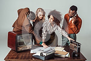 multicultural retro styled journalists at table with radio television and newspapers