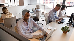 Multicultural staff business people sitting at desks working in office