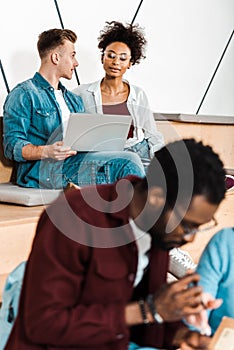 Multicultural students in glasses using laptop