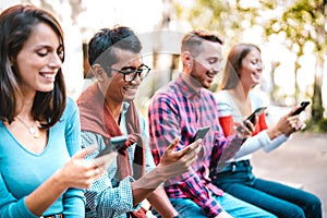 Multicultural students laughing using smartphone at university college campus - Young people friends