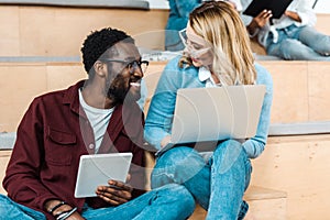 Multicultural students using digital tablet and laptop in lecture hall