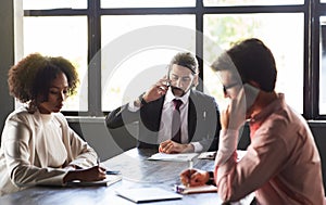 Multicultural team sitting at meeting room against window at office