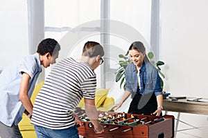 multicultural teenagers playing table football