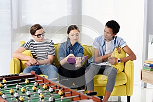 multicultural teenagers reading book on sofa