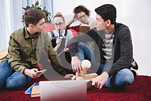 multicultural teenagers studying with laptop