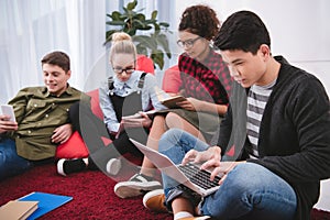 multicultural teenagers studying with laptop