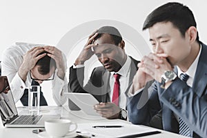 multicultural tired businessmen using tablet together during meeting