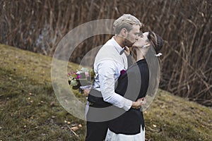 Multicultural weddings and marriages. Outdoor wedding photoshoot. Blond bearded Scandinavian husband kissing his long