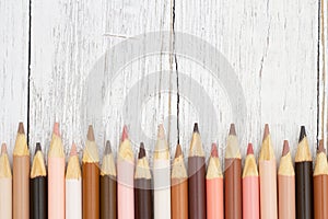 Multiculture skin tone color pencils background on weathered wood photo