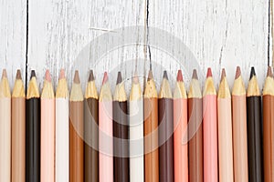 Multiculture skin tone color pencils background on weathered wood photo