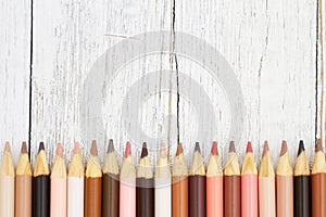 Multiculture skin tone color pencils background on weathered wood photo