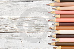 Multiculture skin tone color pencils crayons background on weathered wood photo