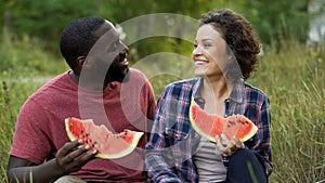 Multiethnic beloved smiling enjoying yummy watermelon, summer picnic outdoors