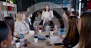 Multiethnic business people clap to successful happy middle aged brunette female coach speaking at office team meeting.