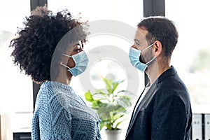 Multiethnic business people with hygienic mask while looking together at eyes in the office