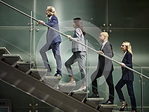 Multiethnic business people walking on steps in modern office
