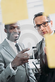 multiethnic businessmen looking at sticky notes on meeting