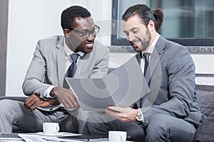 multiethnic businessmen smiling and reading document