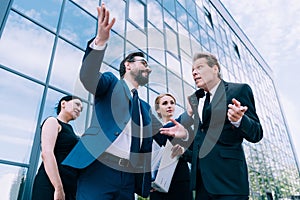 Multiethnic businesspeople having discussion near modern office building