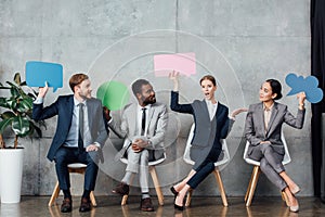 Multiethnic businesspeople holding speech bubbles and thought bubble while sitting in